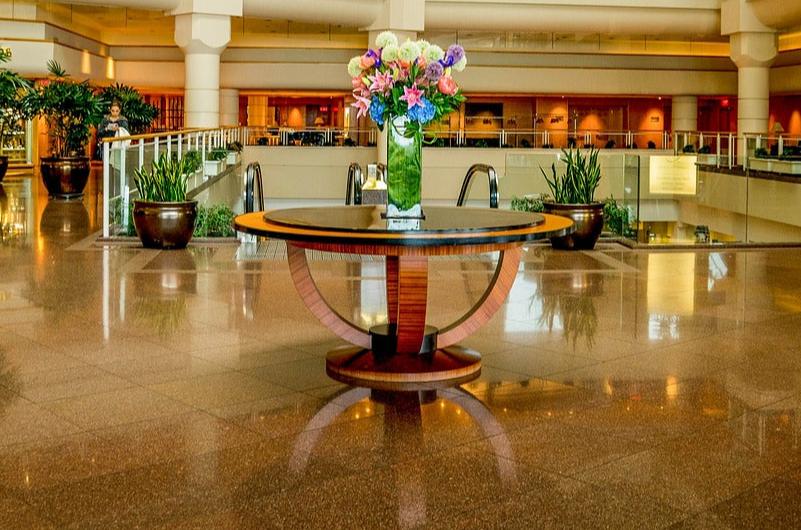 Arreglo floral colorido en el lobby de un edificio, colocado sobre una mesa central de diseño moderno. Parte del servicio de ornamentación floral de Las Flores de la Reina para oficinas y edificios.