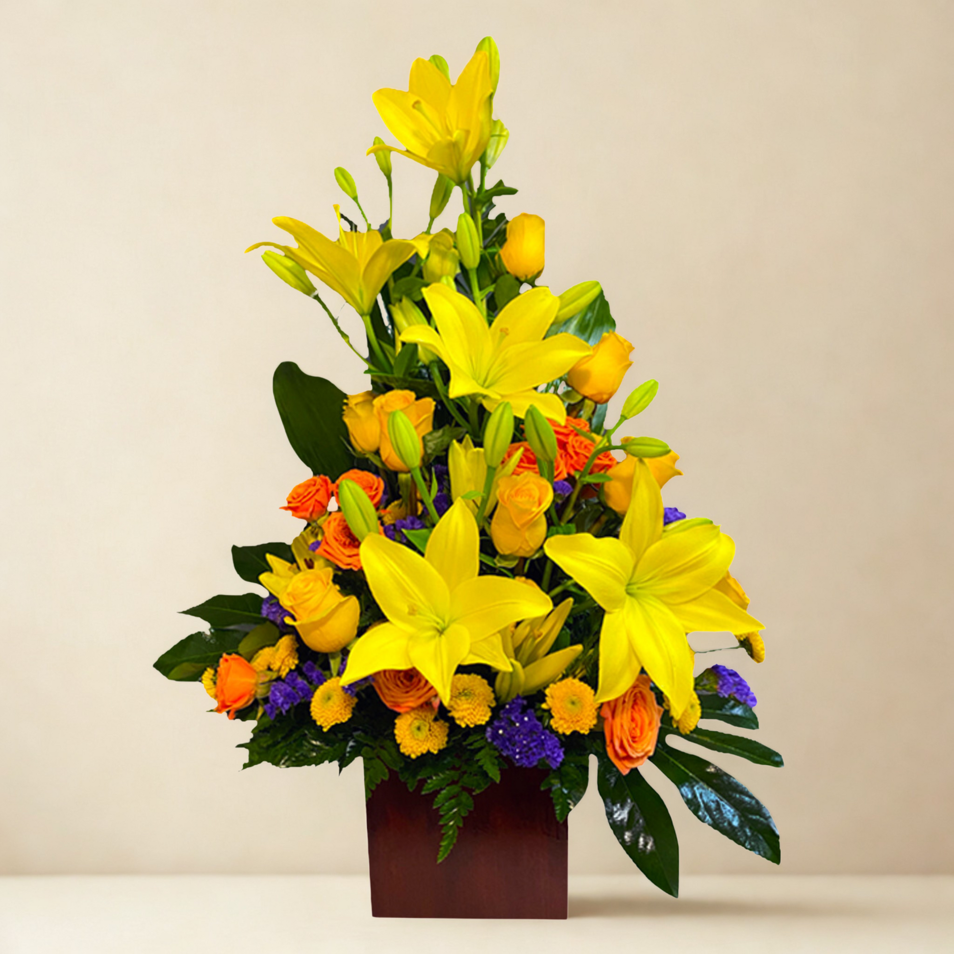 Arreglo floral en tonos amarillos "Brillo de Lilium", compuesto por Lilium, rosas amarillas, maules lila, Lisianthum y follaje verde, presentado en una caja de madera rústica.